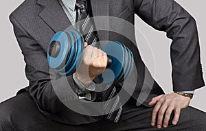 Businessman in a suit is training with dumbbell. Concept: business training