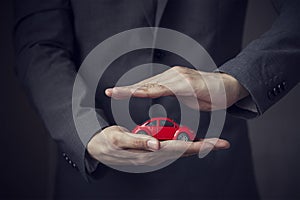 Businessman in suit with two hands in position to protect a car