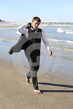 Businessman in suit walking barefoot on beach