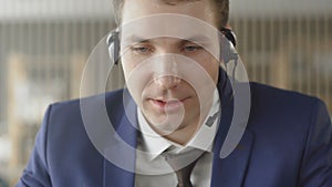 Businessman in suit wear headset talking looking at laptop making notes, male customer support manager skyping on