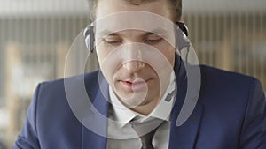 Businessman in suit wear headset talking looking at laptop making notes, male customer support manager skyping on