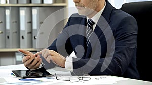 Businessman in suit working in office dialing phone, using financial application