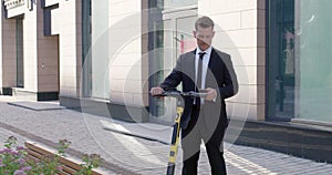 businessman in suit working online on smarphone while standing with electric scooter
