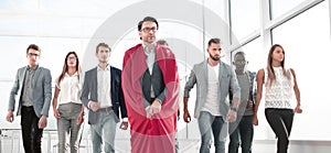 Businessman in a superhero cloak leads a business team