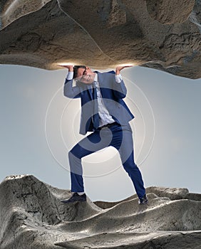 Businessman supporting stone under pressure