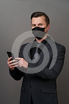 Businessman with surgical medical mask using mobile phone