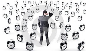 Businessman surrounded by alarm clocks