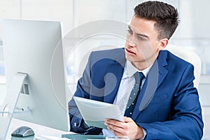 Businessman synchronizing digital tablet with computer.