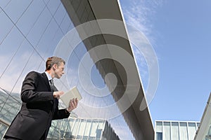 Businessman with tablet that looks far into the sky, in a scene of urban building, cloud computing