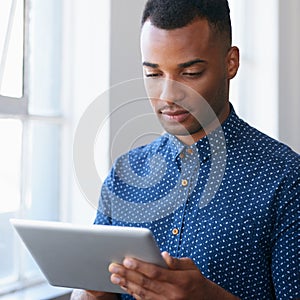 Businessman, tablet and online at window for communication, internet search and networking in office. Entrepreneur