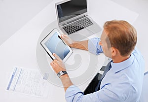 Businessman with tablet pc and papers in office