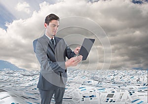 Businessman on tablet in sea of documents under sky clouds