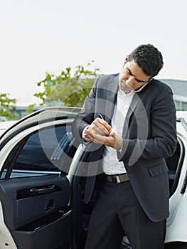 Businessman Takes Notes On Palm Of Hand During Phone Call