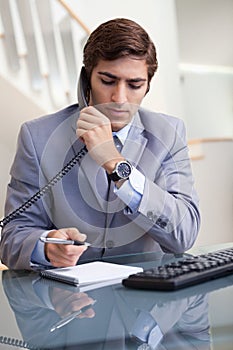 Businessman taking notes while on the phone