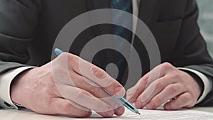 Businessman taking notes or signing contract, pen and document, man in formal jacket. Close up hand