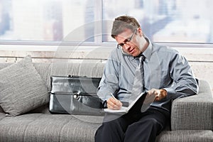 Businessman taking notes on sofa