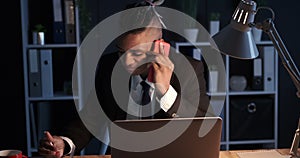 Businessman taking notes using mobile phone and laptop at night office