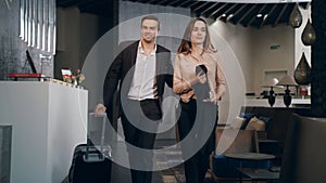 Businessman taking room key at hotel reception. Traveling couple settling hotel