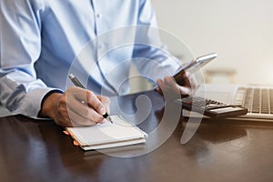 Businessman talk mobile phones and take notes on their notebooks while working on laptop computers, online business, work from