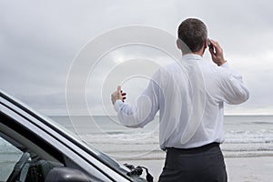 Businessman talking on cell phone at the sea