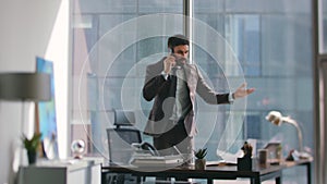 Businessman talking cellphone nervously standing office looking documents.