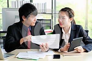 Businessman is talking with his collegue and point to paper chart in the modern office