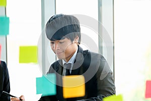Businessman is talking with his collegue and point to paper chart in the modern office. In front of man has transparence glass