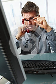 Businessman talking on landline phone in office photo
