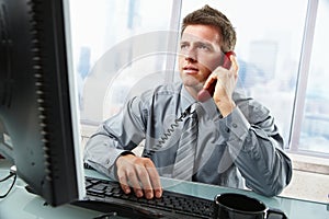 Businessman talking on landline phone in office photo