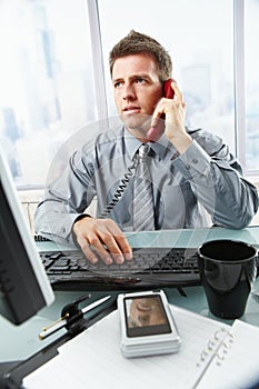 Businessman talking on landline phone in office photo