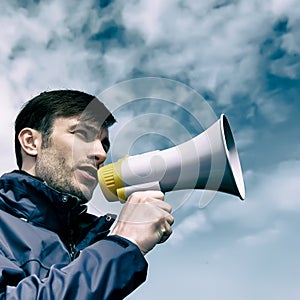 Businessman talking in a megaphone against the sky.