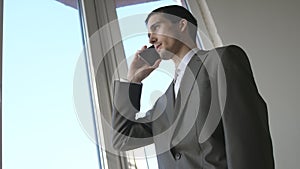 The businessman talking mobile phone near the panoramic window.