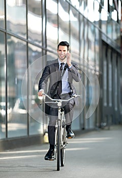 Businessman talking with mobile phone and riding a bicycle
