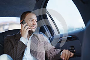 Businessman Talking On Mobile Phone Travelling In Limousine