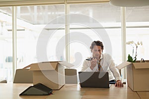 Businessman talking on mobile phone while using laptop in the conference room