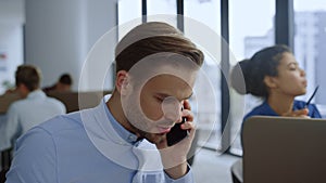 Businessman talking on mobile phone at workplace. Team working in open space