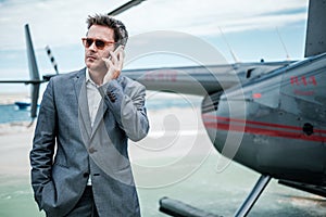 Businessman talking over the phone near private helicopter