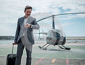 Businessman talking over the phone near private helicopter