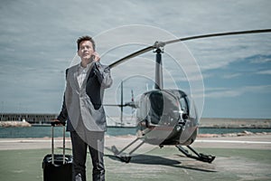 Businessman talking over the phone near private helicopter