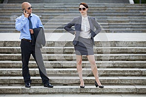 Businessman talking on phone while businesswoman standing on steps