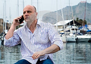 Businessman talking on the phone close to the luxurious harbor
