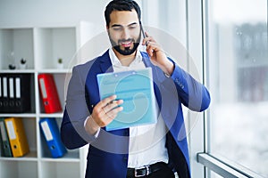 Businessman talking on the phone in office looking out the window