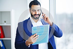 Businessman talking on the phone in office looking out the window