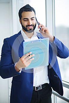 Businessman talking on the phone in office looking out the window