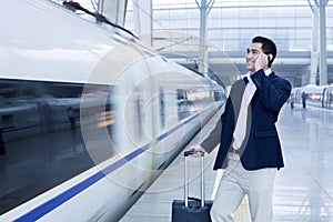 Businessman talking on the phone on the railroad platform by a high speed train in Beijing