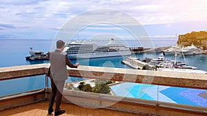 Businessman talking phone on restaurant terrace, view of private harbor, yachts