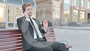 Businessman Talking on Phone while Sitting Outdoor on Bench