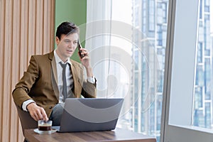 Businessman talking phone to manager while sitting near window. Ornamented.