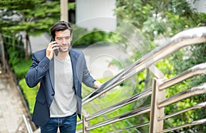 The businessman talking with smart phone on his way. Feeling happy and relaxing, Casual young businessman wearing suit jacket