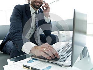 Foreground businessman talking on a smartphone